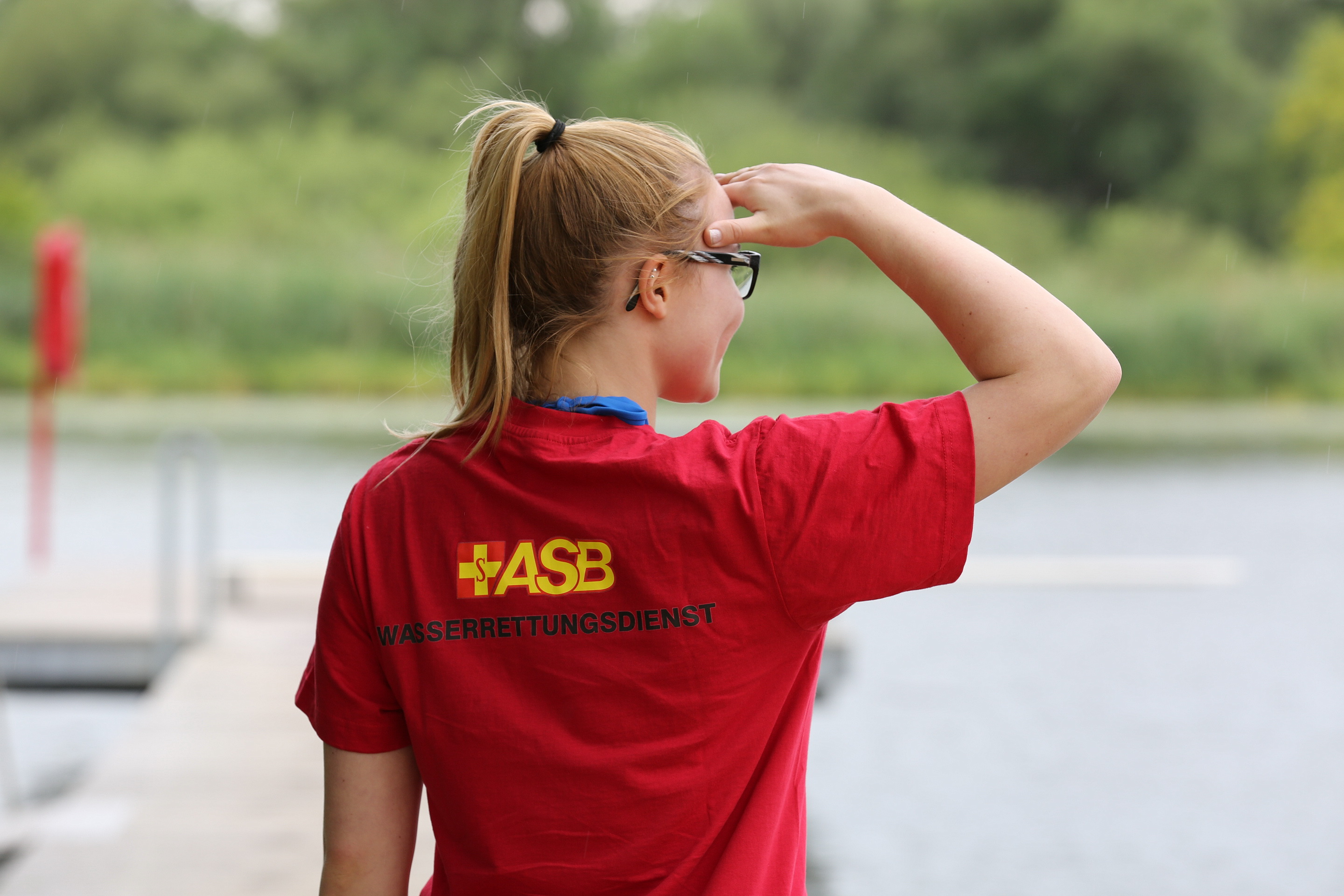 Mitarbeiterin der Wasserrettung schaut über den See